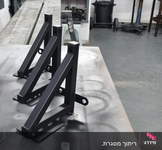 שלושה מסגרות מתכת שחורות על שולחן עבודה